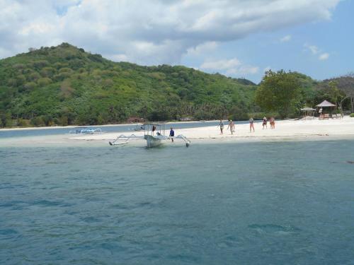 a group of people on a beach with a boat in the water at Silver Fern Beach Retreat in Sekotong