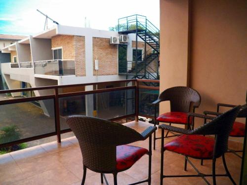 a balcony with chairs and a table and a building at Hotel Puesta del Sol by Nobile in Encarnación