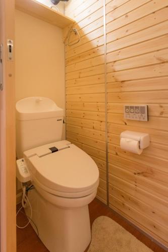 a bathroom with a toilet in a wooden wall at Phottage inn Biei in Biei