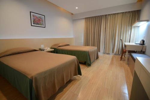 a hotel room with two beds and a desk at Charoen Hotel in Udon Thani