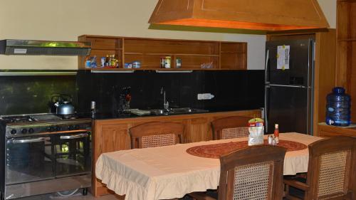 a kitchen with a table and a black refrigerator at Villa Latebra in Lovina