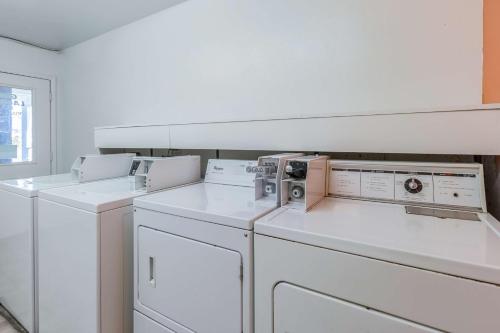 a white laundry room with three washer and dryers at Motel 6-Beaverton, OR in Beaverton