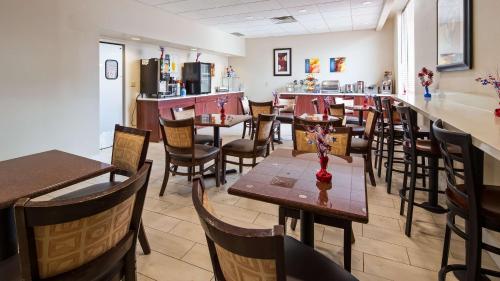 Un restaurante con mesas y sillas y un bar. en Best Western Airport Inn & Suites Cleveland, en Brook Park
