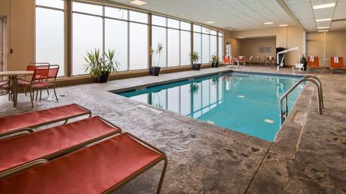 a large swimming pool with red chairs and a table at Best Western Airport Inn & Suites Cleveland in Brook Park