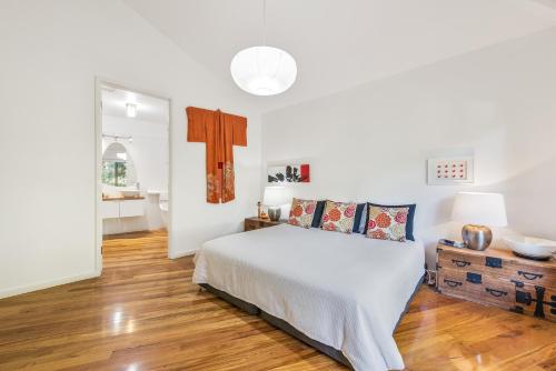 a white bedroom with a bed and a wooden floor at Dalrymples Guest Cottages in Marysville