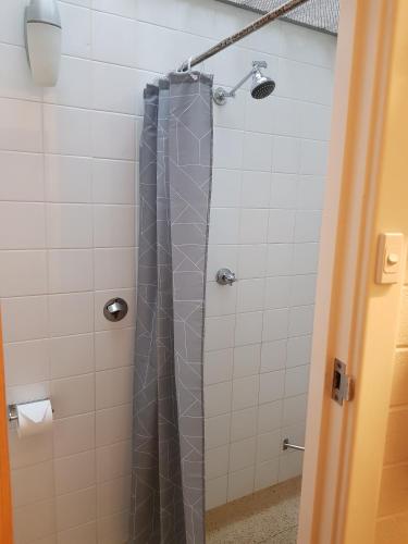 y baño con ducha con cortina gris. en Morphett Arms Hotel, en Adelaida