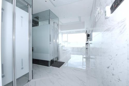 a white bathroom with a glass shower and a mirror at Gwanganli Hotel 1 in Busan