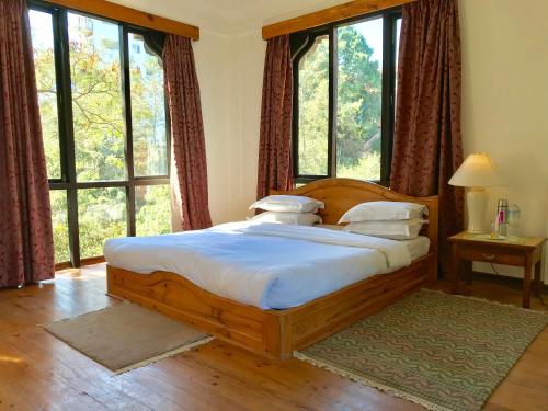 a bedroom with a large wooden bed in front of windows at The Fort Resort in Nagarkot