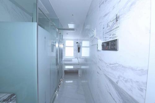 a bathroom with white walls and white marble floors at Gwanganli Hotel 1 in Busan