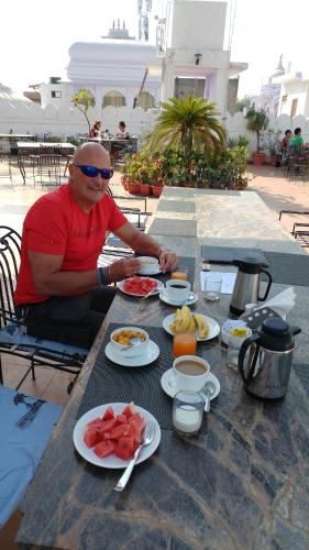 Nirvana Home في جودبور: رجل يجلس على طاولة مع أطباق من الطعام