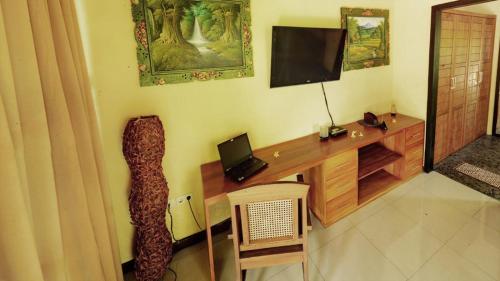 a room with a desk with a television on the wall at Villa Latebra in Lovina