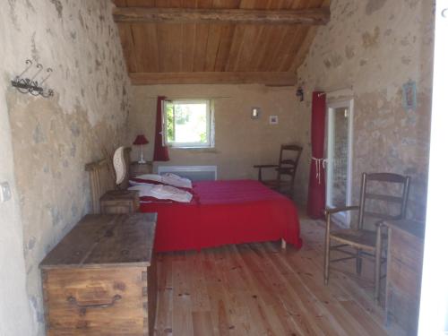 een slaapkamer met een rood bed en een tafel en stoelen bij chambres du Domaine de Bombes in Mostuéjouls
