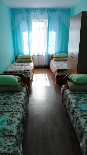 ジヴェエヴォにあるDiveevskoe podvorieのベッド3台と窓が備わる客室です。