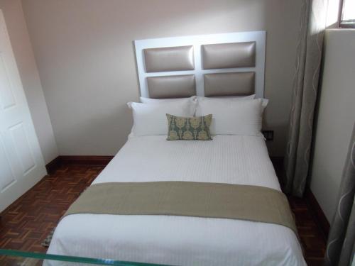 a bedroom with a large white bed with two pillows at The Musafer Travel Lodge in Pietermaritzburg