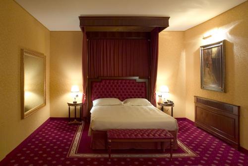 a bedroom with a bed and a bench in it at Hotel Maxim in Peschiera Borromeo