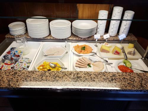 a buffet with plates and food on a counter at Hotel Eremitage in Arlesheim