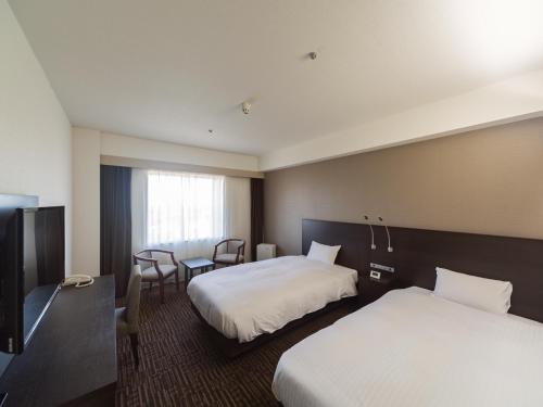 a hotel room with two beds and a television at KKR Hotel Nagoya in Nagoya