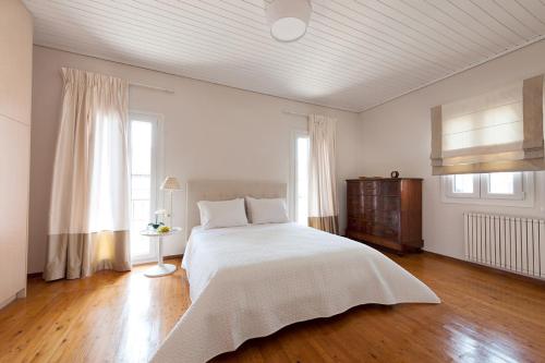 a white bedroom with a large bed and wooden floors at Corfu Town Stylish Apartment in Corfu Town