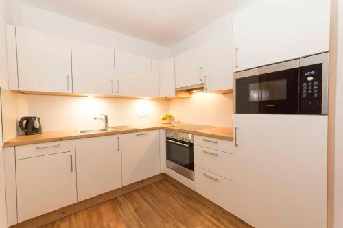 a kitchen with white cabinets and black appliances at Hubergut Appartements in Radstadt