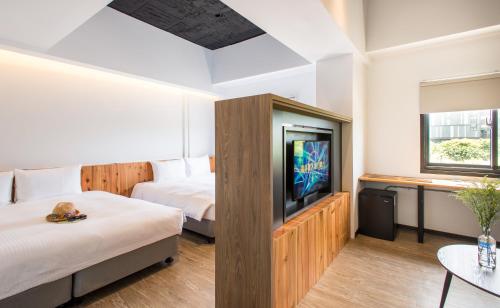 Habitación de hotel con 2 camas y TV de pantalla plana. en Traveller Inn TieHua Cultural and Creative Hotel, en Taitung