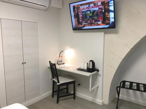 a room with a desk and a tv on the wall at Hôtel La Fabrique in La Rochelle