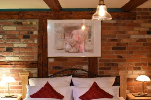 um quarto com uma parede de tijolos e uma cama com almofadas vermelhas em Ferienwohnung Casa da Maria em Langelsheim