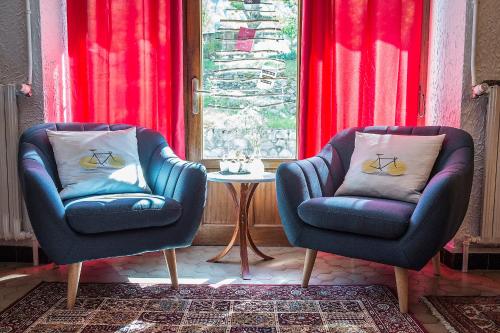 two chairs and a table in a room with red curtains at Hôtel Le Cassini in Le Freney-dʼOisans