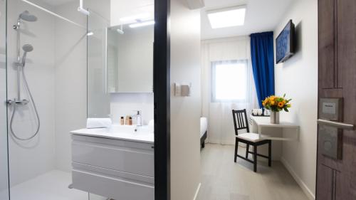 une salle de bain blanche avec un lavabo et une douche dans l'établissement Hôtel La Fabrique, à La Rochelle