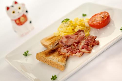 Un plato de desayuno con huevos, tocino y tostadas. en Chalet Matsuzaka - chambres d'hôtes de luxe, en La Rosière
