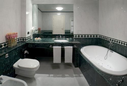 a bathroom with a tub and a toilet and a sink at Hotel Maxim in Peschiera Borromeo