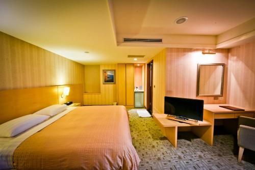 淡水にあるサンライズ　ビジネス　ホテル　淡水のベッド、デスク、テレビが備わるホテルルームです。