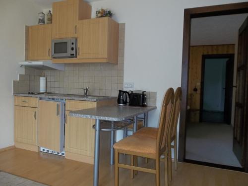 una cocina con armarios de madera, mesa y sillas en Ferienwohnung Günschmann en Hausen