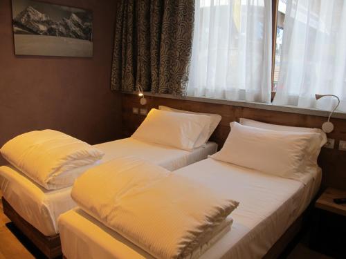 two twin beds in a room with a window at MH Olen Boutique Hotel in Alagna Valsesia