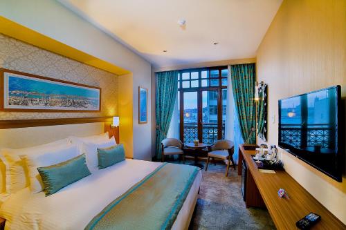 イスタンブールにあるホテル モーメント ゴールデン ホーンの大型ベッドとテレビが備わるホテルルームです。