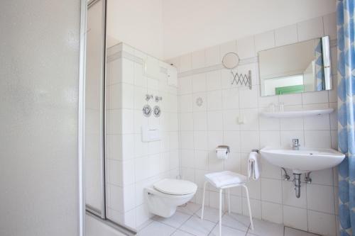 a white bathroom with a toilet and a sink at Gästehaus Villa Rose in Dürrröhrsdorf
