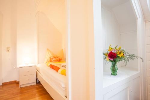 a bedroom with a bed with a vase of flowers on a table at Gästehaus Villa Rose in Dürrröhrsdorf