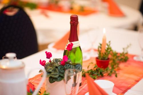 a bottle of wine sitting on a table with flowers at Gästehaus Villa Rose in Dürrröhrsdorf