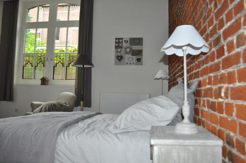 a bedroom with a bed and a brick wall at Au Cœur du Jardin in Lille