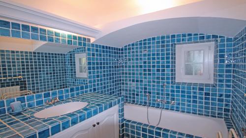 ein blau gefliestes Bad mit einem Waschbecken und einer Badewanne in der Unterkunft Villa Cavok in Sainte-Maxime