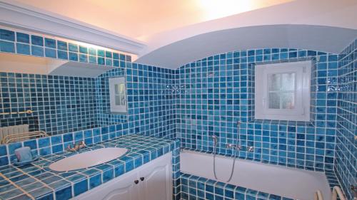 une salle de bain carrelée bleue avec un lavabo et une baignoire dans l'établissement Villa Cavok, à Sainte-Maxime