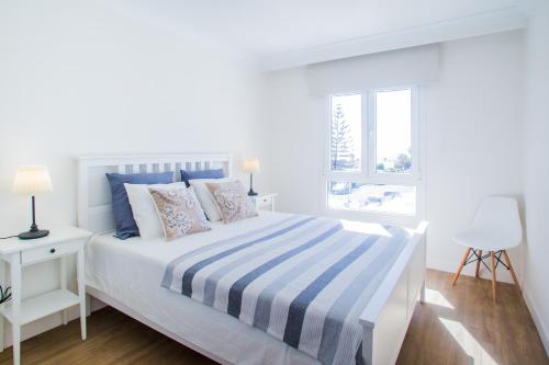 プラヤ・オンダにあるFlower Beach Suite 26の白いベッドルーム(ベッド1台、窓付)