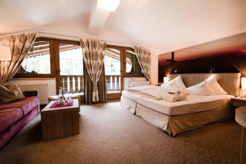 a bedroom with a large bed and a couch at Olympia-Relax-Hotel Leonhard Stock in Finkenberg