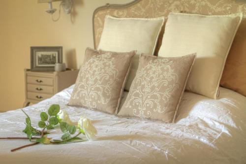 uma cama branca com almofadas e uma flor em Thermes Oppidum em Theux