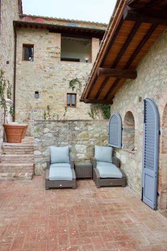 a patio with two lounge chairs and a stone building at Borgo Argiano in Castelnuovo Berardenga