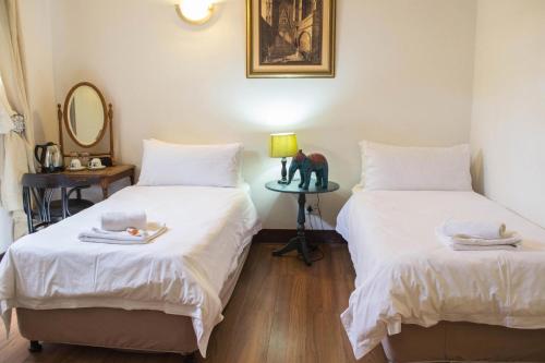 a room with two beds and a table with a mirror at Premier Hotel and Spa Cullinan in Cullinan