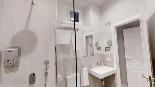 een witte badkamer met een douche en een wastafel bij Monumental Building Casa de la Moneda Center&Sweet in Sevilla