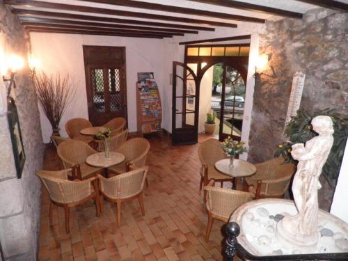 a restaurant with tables and chairs and a statue at Hôtel Saint Jean in Vals-les-Bains
