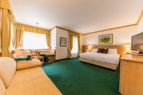 une chambre d'hôtel avec un lit et une télévision dans l'établissement Hotel La Maison Wellness & Spa, à Alleghe