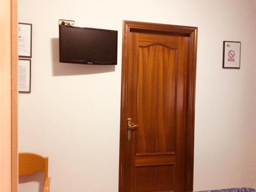una puerta de madera con TV de pantalla plana en la pared en Hostal del Carmen, en Terrassa