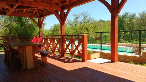 une terrasse en bois avec une pergola et une piscine dans l'établissement Le Bois De Barthes, à Lavercantière